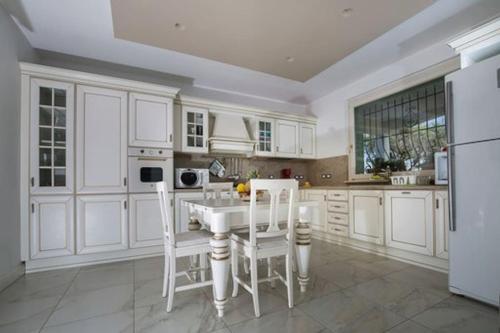 a kitchen with white cabinets and a white table and chairs at Villa MERAVIGLIA, heated pool, 16 km from the sea in Ascoli Piceno