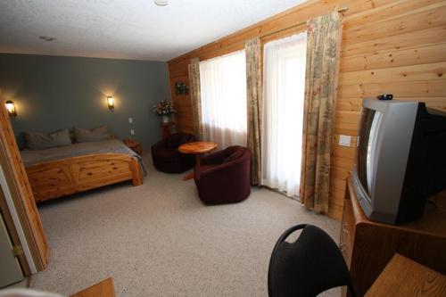 a bedroom with a bed and a tv in a room at Glenogle Mountain Lodge and Spa in Golden