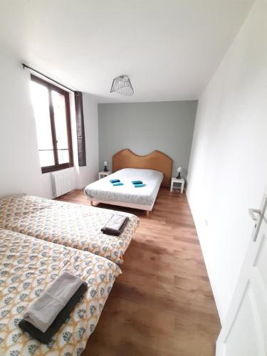 2 łóżka w pokoju z białymi ścianami i drewnianą podłogą w obiekcie Résidence du Houx - 4 (Astérix, Aéroport CDG, Chantilly, Parc expos...) w mieście Survilliers