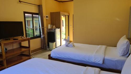 a room with two beds and a tv and a television at Thongplu Beach Resort Samui in Ban Thong Phlu