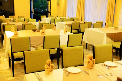 a dining room with white tables and chairs with napkins at Meilin International Hotel in Kampala