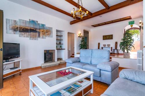 ein Wohnzimmer mit einem blauen Sofa und einem TV in der Unterkunft Casa Honiol, private and spacious villa with sea views in Cala en Porter