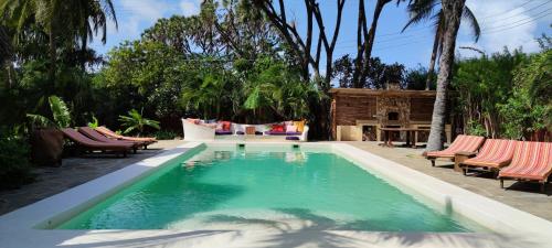 a swimming pool with chaise lounges and a house at Lions' Luxury Eco Resort & Spa in Malindi