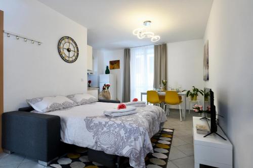 een slaapkamer met een groot bed met een klok aan de muur bij Aria Apartment - Free Parking in Bioggio