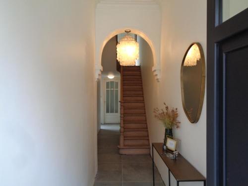 a hallway with a staircase and a mirror on the wall at Sweet Alice Holiday Home in Ieper