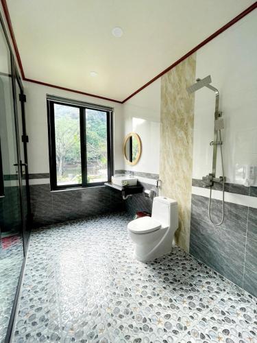 a bathroom with a toilet and a glass shower at Trang an green river homestay in Ninh Binh