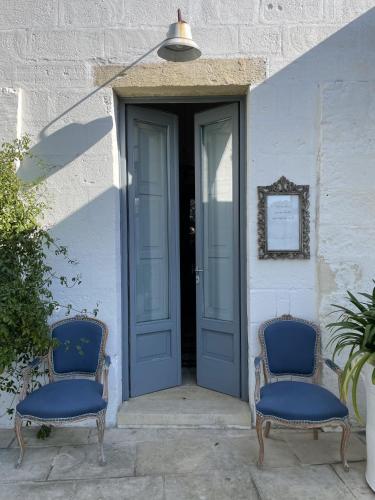 two blue chairs sitting in front of a door at Masseria Spartivento in Conca Specchiulla