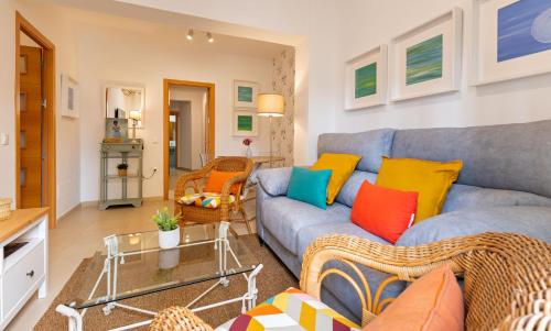 salon z niebieską kanapą i kolorowymi poduszkami w obiekcie San Vicente Apartamento, 5 pax, Centro Historico w Sewilli