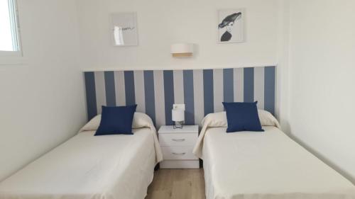 2 bedden in een kleine kamer met blauwe kussens bij La Casilla de Nerja in Nerja