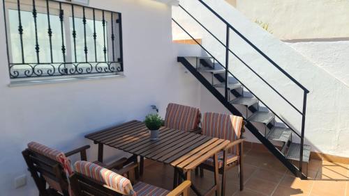 een houten tafel met stoelen en een trap bij La Casilla de Nerja in Nerja