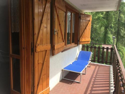 a blue chair sitting on a porch with wooden windows at CASA VACANZE CRISSOLO in Crissolo