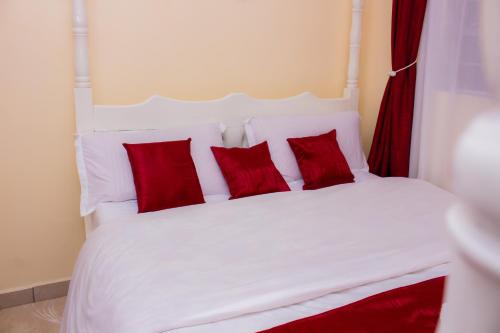 Una cama blanca con almohadas rojas. en Homes By Mwema en Nairobi