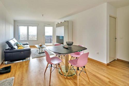 - un salon avec une table et des chaises roses dans l'établissement Magnifique F3 à moins de 15 min de la défense, à Nanterre
