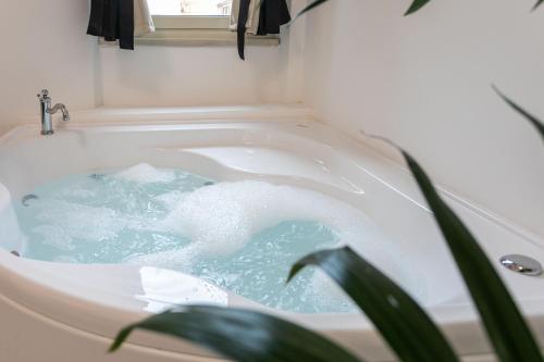 a bath tub filled with blue water next to a plant at Re di Roma Rooftop in Rome