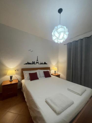 Un dormitorio con una gran cama blanca y una lámpara de araña. en Design apartments - B en Siniscola