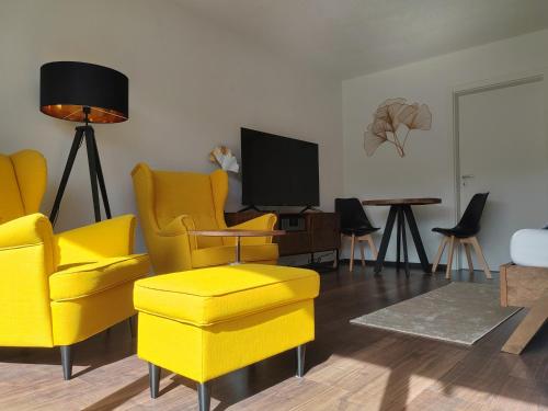a living room with yellow chairs and a tv at Ferienwohnung Elbtraum in Pirna