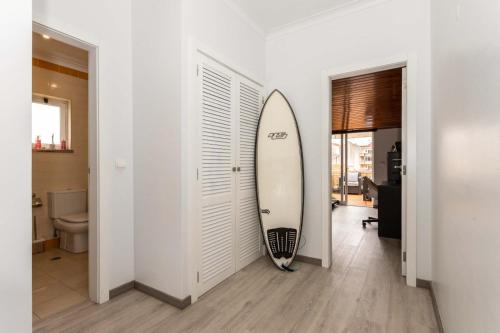 ein Surfbrett, das in einem Raum gegen eine Wand lehnt in der Unterkunft THE ATTIC - Caparica Beach and Surf Apartment in Costa da Caparica