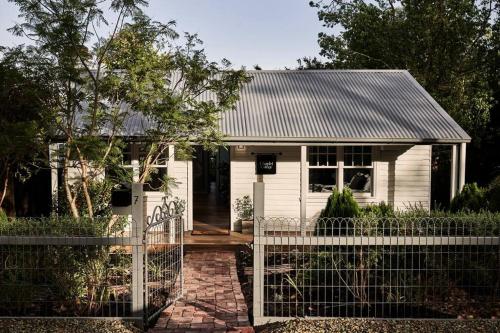 a white house with a fence in front of it at Chaplet Cottage Luxury Healesville Cottage in Healesville