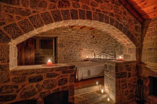 a bedroom with a bed and candles in a stone wall at Achelatis Traditional Guest Houses in Areopoli