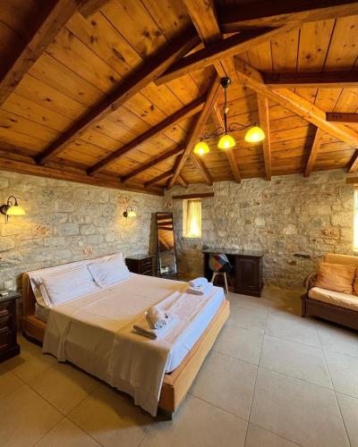 a bedroom with a large bed and a stone wall at Achelatis Traditional Guest Houses in Areopolis