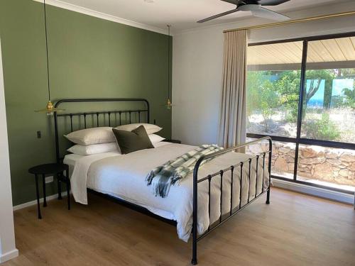 Un dormitorio con una cama con paredes verdes y una ventana en Kidman's Rest, en The Range