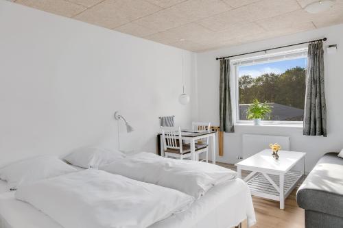 a white bedroom with a bed and a window at LOasen Vesterhede in Hejnsvig