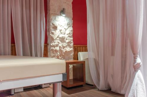 a bedroom with a bed and curtains and a lamp at Hagiati Anastasiou Hotel & Spa in Naousa Imathias