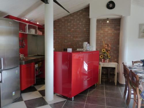 une cuisine avec des armoires rouges et une table dans l'établissement Maison 3 pièces avec jardin clos, terrasse, et équipements à 1,9 km de la plage - 6 couchages - FR-1-224-779, à Saint-Gilles-Croix-de-Vie