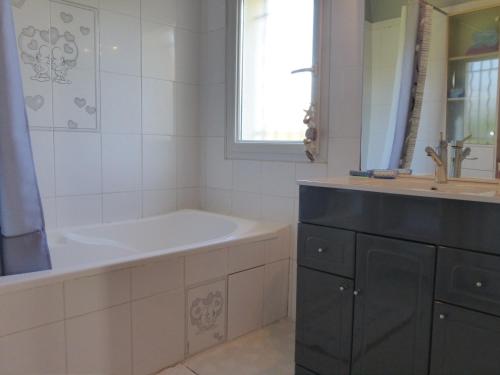 une salle de bain avec une baignoire et un lavabo dans l'établissement Maison 3 pièces avec jardin clos, terrasse, et équipements à 1,9 km de la plage - 6 couchages - FR-1-224-779, à Saint-Gilles-Croix-de-Vie