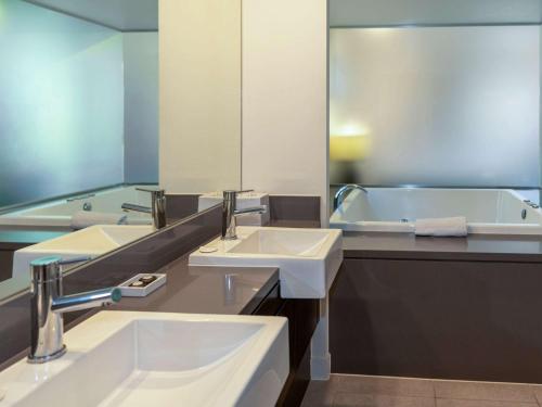 a bathroom with two sinks and a bath tub at Pullman Port Douglas Sea Temple Resort and Spa in Port Douglas