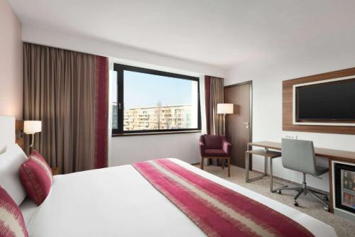 クラヨーヴァにあるRamada Plaza Craiovaのベッド、デスク、テレビが備わるホテルルームです。