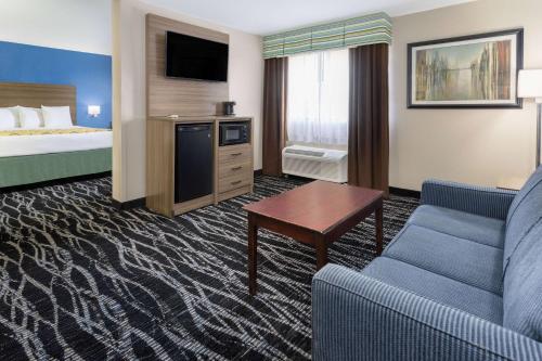 a hotel room with a bed and a couch and a table at Baymont by Wyndham Saraland in Saraland