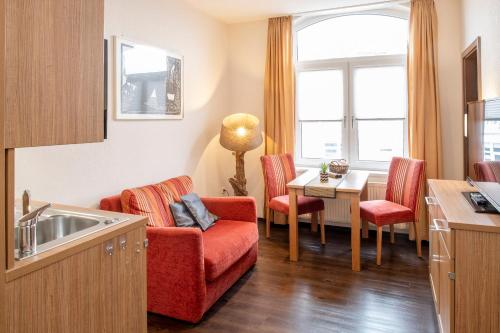 eine Küche mit einem roten Sofa und einem Tisch mit Stühlen in der Unterkunft Appartementhaus Alte Post in Langeoog