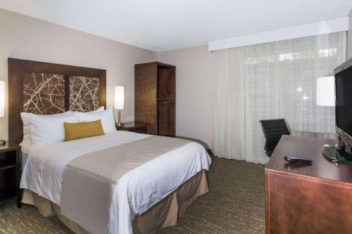 a hotel room with a bed and a television at Wyndham Garden Fresno Yosemite Airport in Fresno