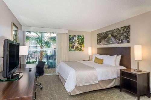 a hotel room with a bed and a flat screen tv at Wyndham Garden Fresno Yosemite Airport in Fresno