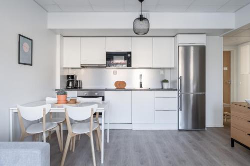 a kitchen with a table and a stainless steel refrigerator at Modern 2BR Apartment with Balcony & Central Location - Hosted by 2ndhomes in Tampere