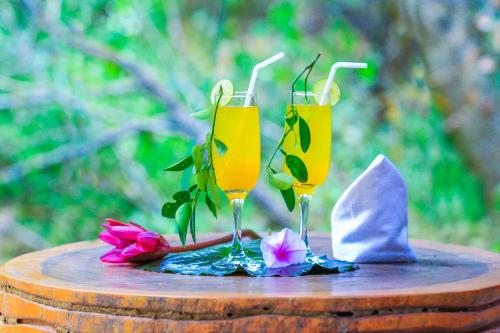 Dois copos de mimosas numa mesa com flores. em The Campers Lodge Yala em Yala