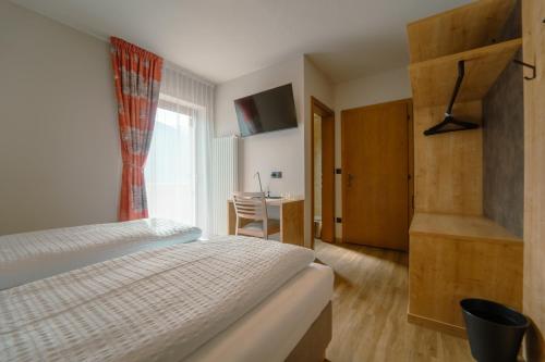 um quarto com uma cama, uma secretária e uma janela em Gasthof Paul em Naz-Sciaves