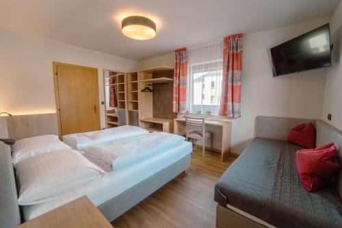 um quarto com uma cama, uma secretária e uma televisão em Gasthof Paul em Naz-Sciaves