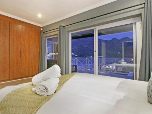 une chambre avec un grand lit avec une grande fenêtre dans l'établissement Villa de la Mer Hout Bay Beachfront, au Cap