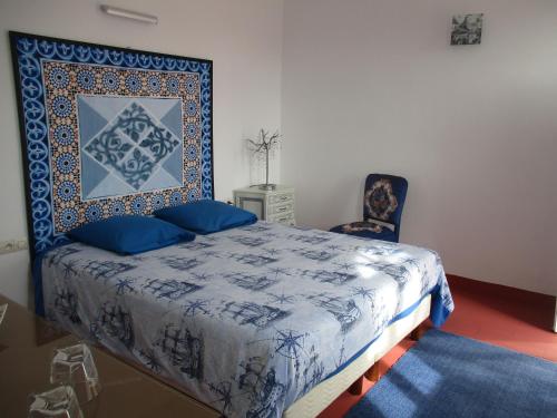 a bedroom with a blue and white bed and a chair at Dar Mozart in Essaouira