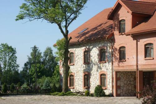 Una casa vieja con un árbol delante. en Hostel Miłosz, en Grabowiec