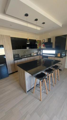 a kitchen with a large counter with chairs and a table at Trilogy Penthouse, Holiday Home, Gozo in Kerċem