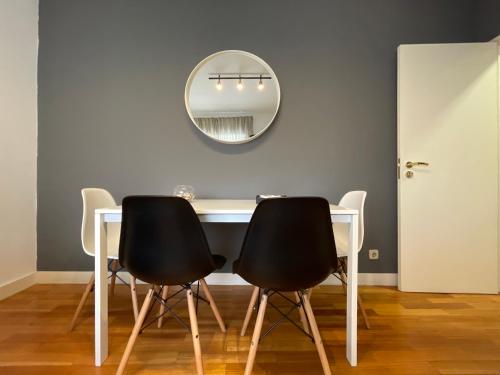 a dining room table with two black chairs and a mirror at Apartments City Center • Collection by Perpetual Relax in Braga