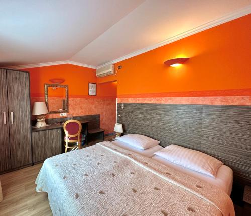 ein Schlafzimmer mit einem großen Bett und einer orangefarbenen Wand in der Unterkunft Hotel Grahor Depandance in Sežana