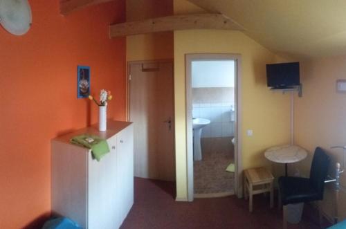 a room with orange walls and a bathroom with a sink at Penzion Cihelna in Brno