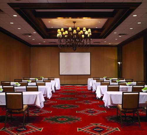 a conference room with white tables and chairs and a projection screen at Red Deer Resort & Casino in Red Deer
