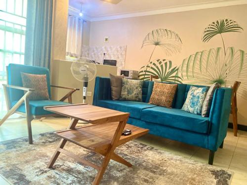een woonkamer met een blauwe bank en een tafel bij Modern Furnished Rooms with Netflix, Kitchen, Living room , Laundry DStv and Free WiFi in Kampala