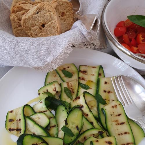 a plate of food with cucumbers and a bowl of bread at Masseria Spartivento in Conca Specchiulla