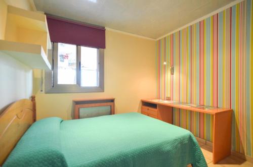 a bedroom with a green bed and a window at Club Villamar - Apartment Amity in Maçanet de la Selva